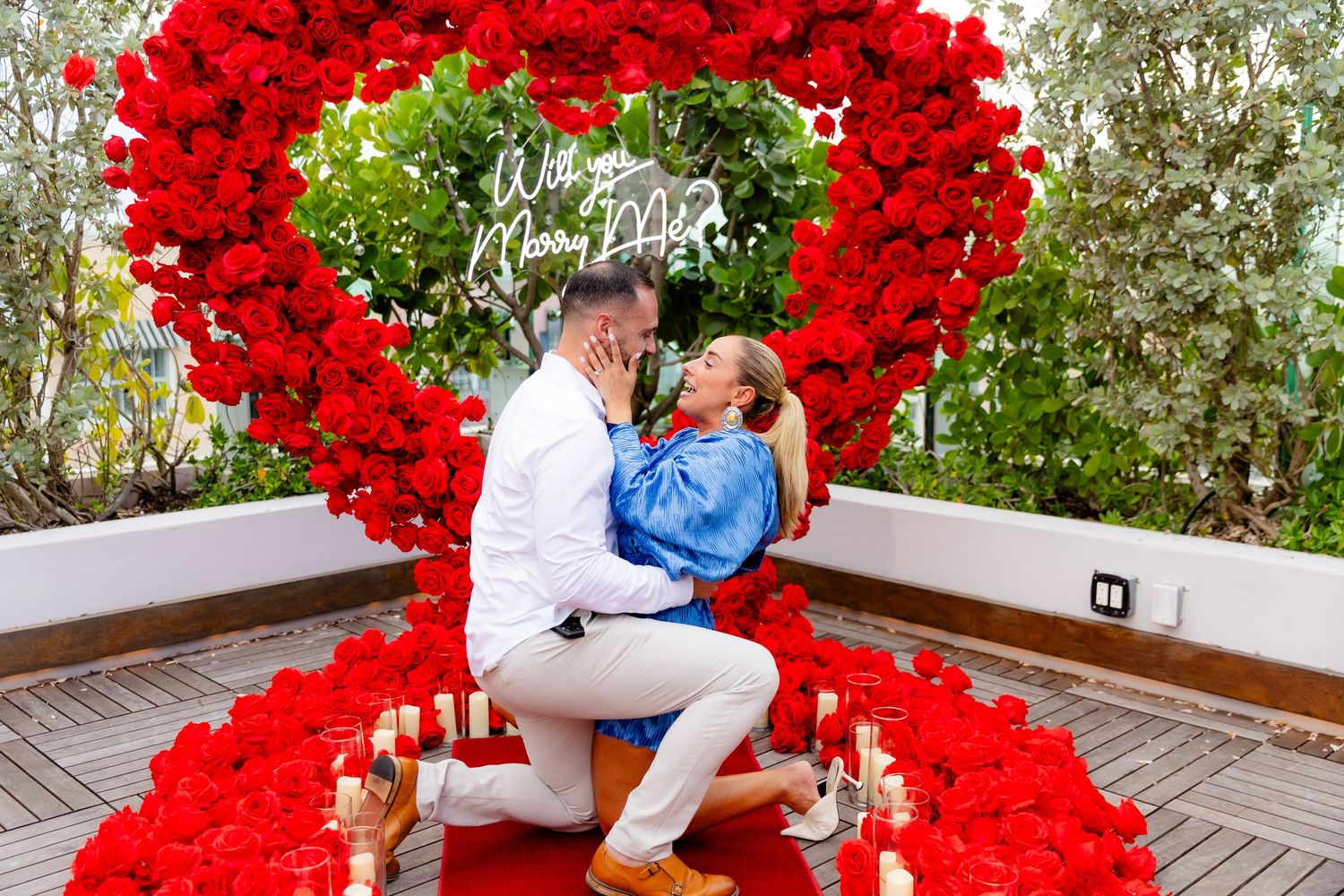 A beautifully decorated proposal setup featuring a large heart made of red roses and white candles.