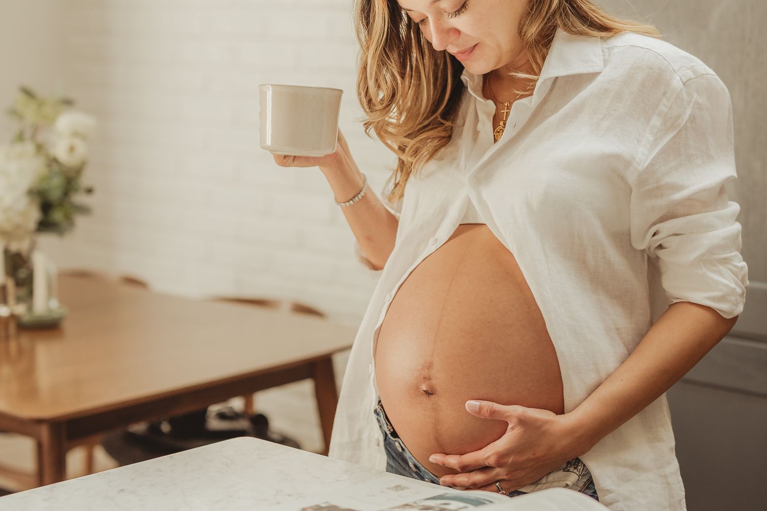 Artistic maternity photos showing a pregnant woman in a white shirt and jeans.