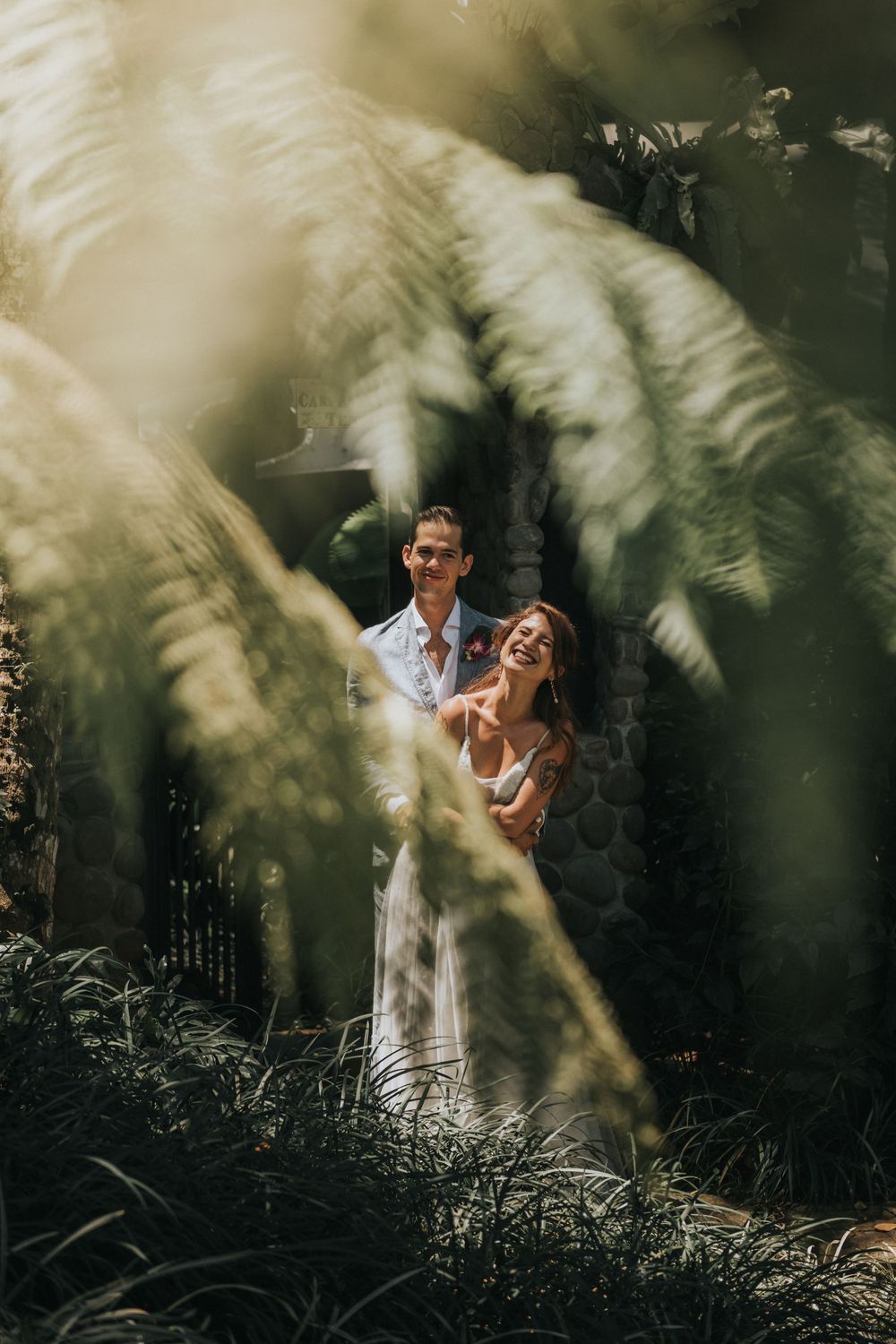 Couple laughs together through soft focus pampas grass in garden setting.