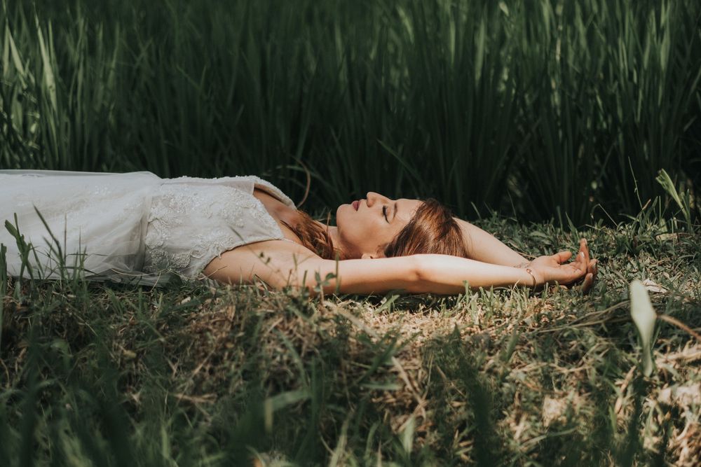 Couple lying in tall grass field during outdoor photo session.