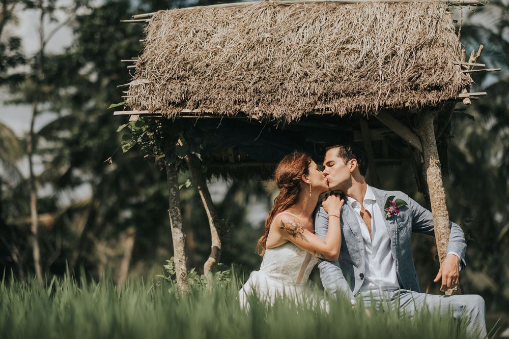 Intimate moment captured under rustic shelter surrounded by green fields.