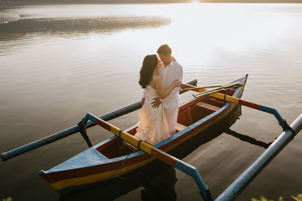 Traditional wooden boats with couple against tranquil water backdrop.