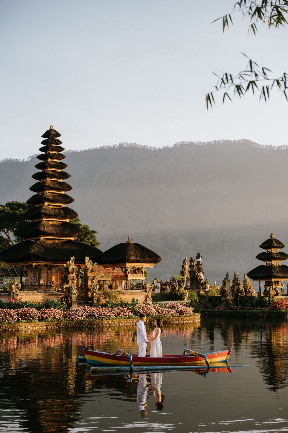 Balinese water temple Pura Ulun Danu Bratan with couple in boat during golden hour.