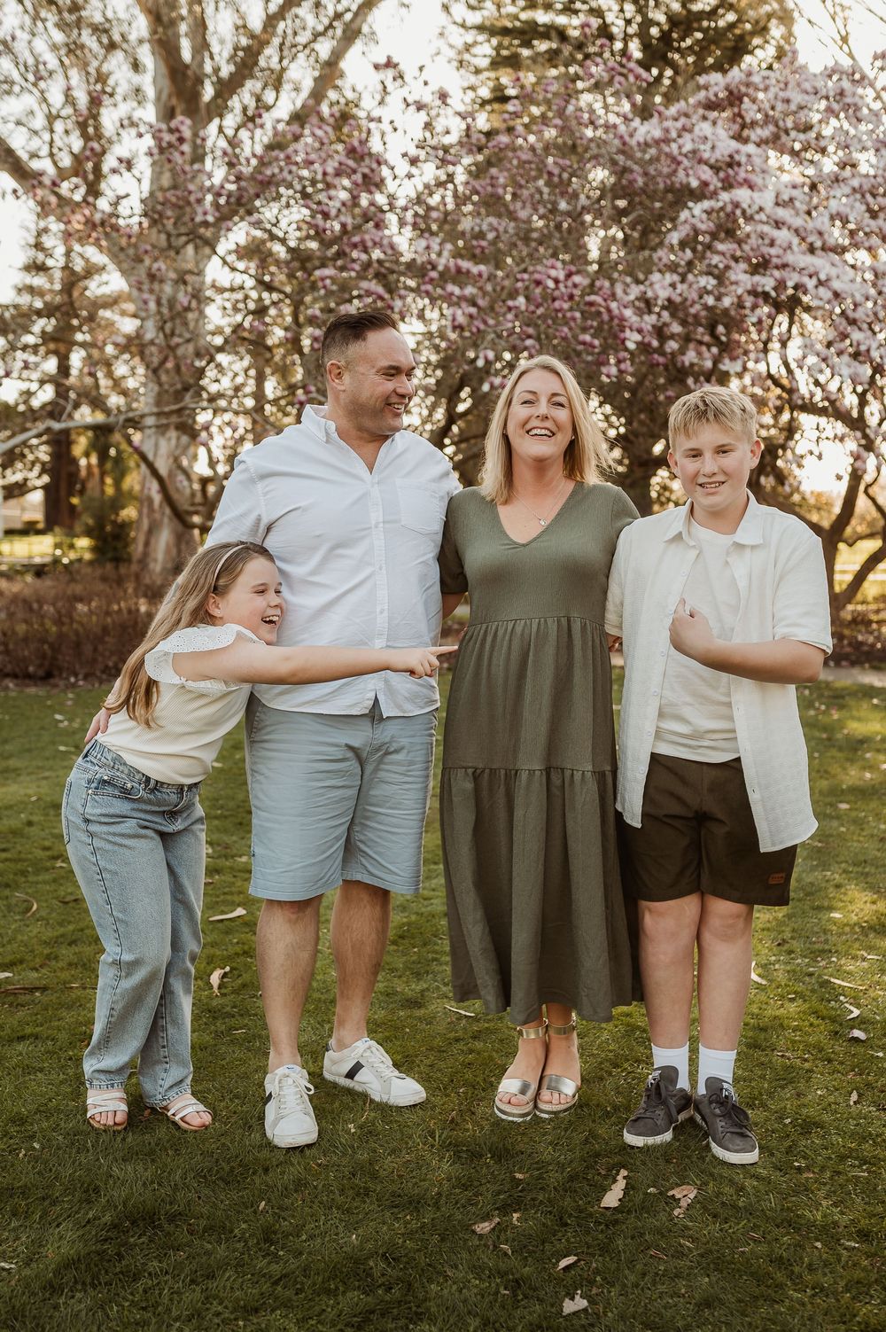 A collage of five candid family photos showing legs and feet gathered outdoors under blooming cherry blossom trees.