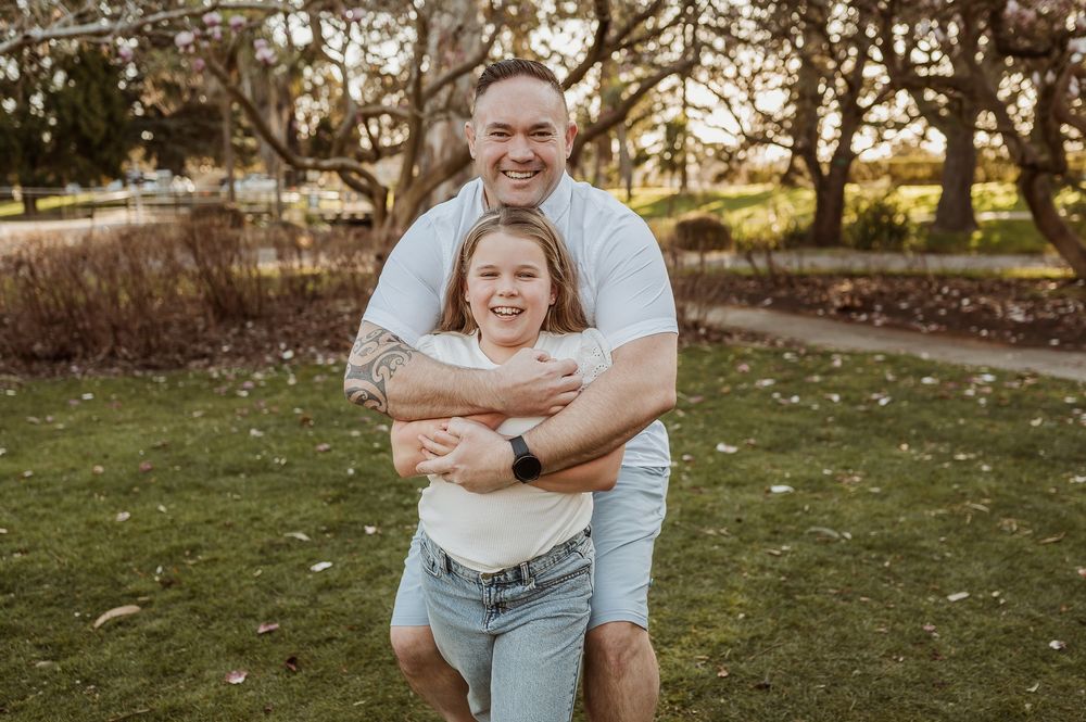 A happy couple shares a playful moment outdoors in a park during golden hour.