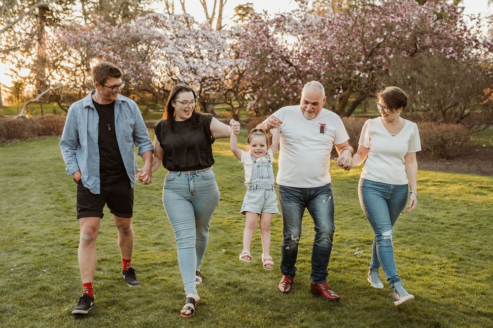A group of people strolling on grass and dancing during golden hour in casual outfits.