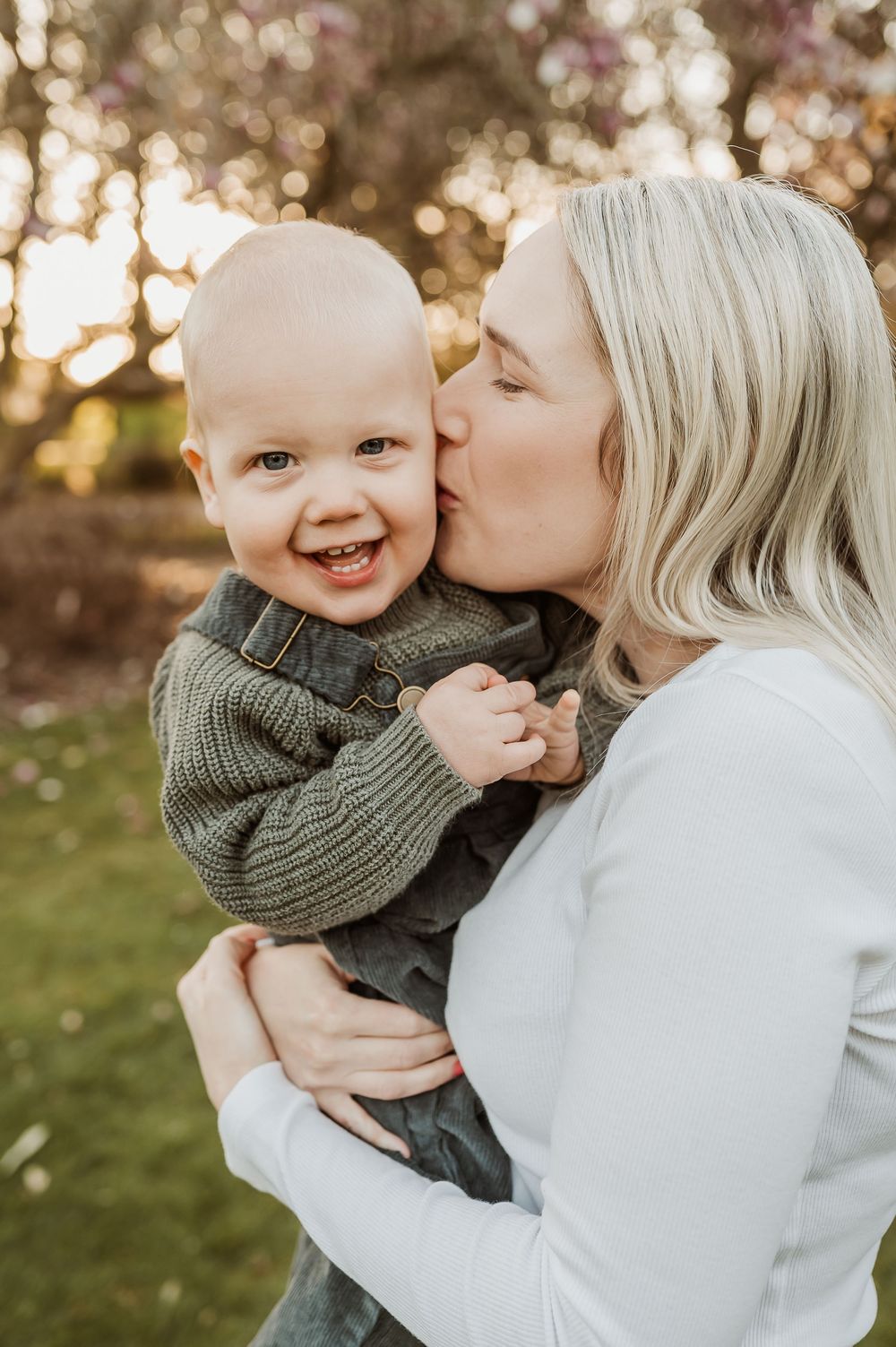 A tender moment between parent and child outdoors with warm golden lighting and natural bokeh effects in the background.