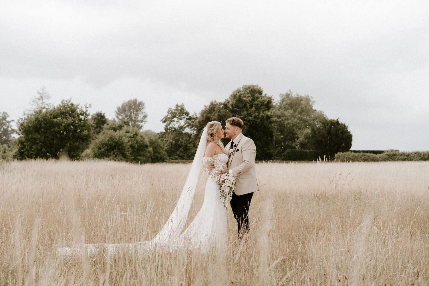 A couple shares a romantic moment in a golden field during their wedding photo session at sunset.
