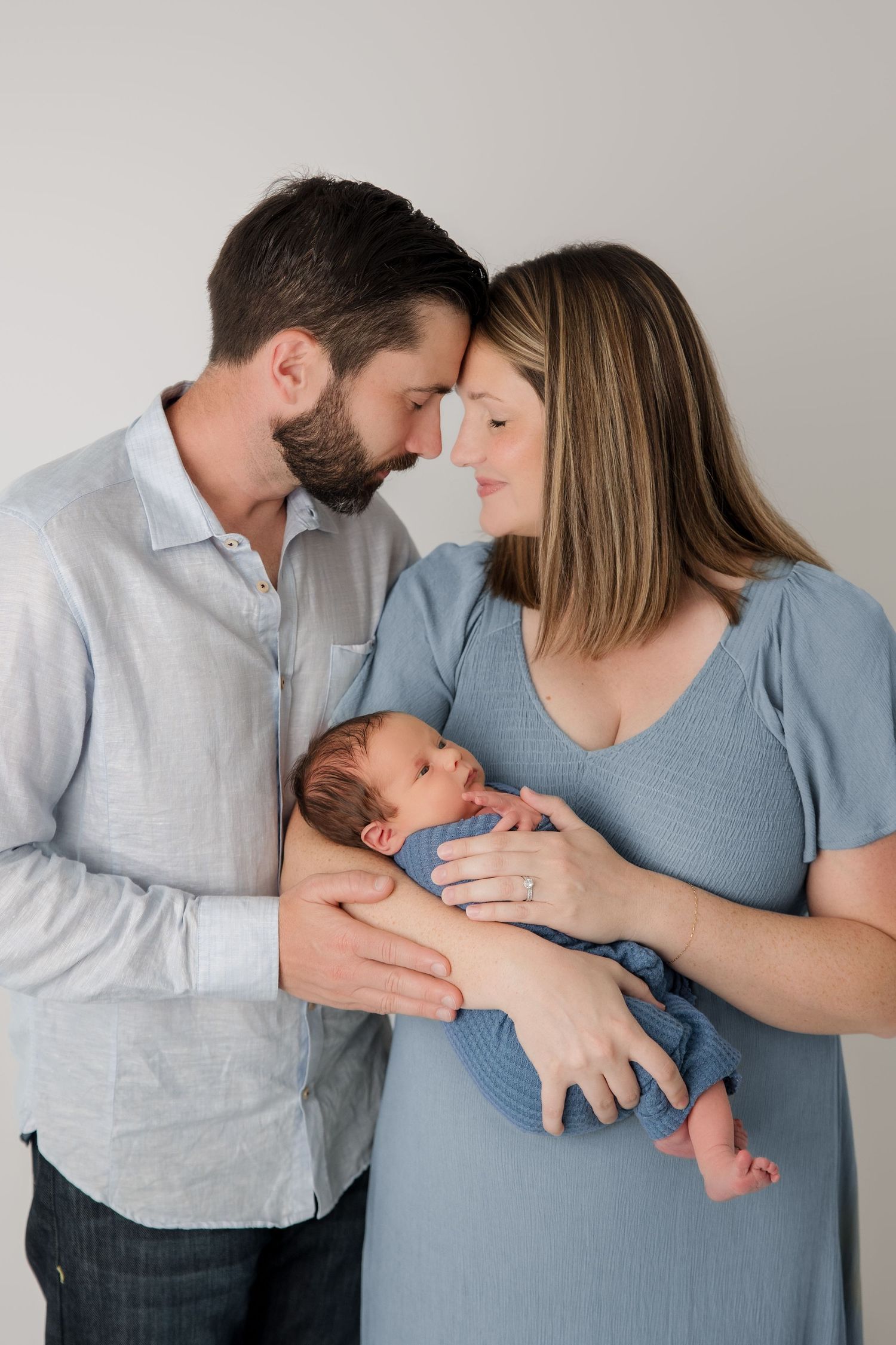 A romantic series of photos showing an intimate couple with a newborn baby against a white background.