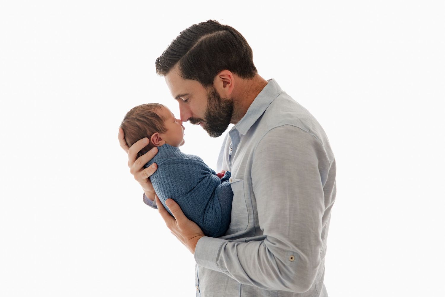 Emotional family moment captured in soft lighting against white background.