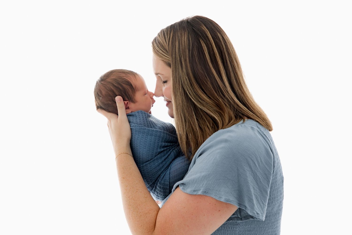 A couple in white and blue clothing share tender moments with their newborn baby.