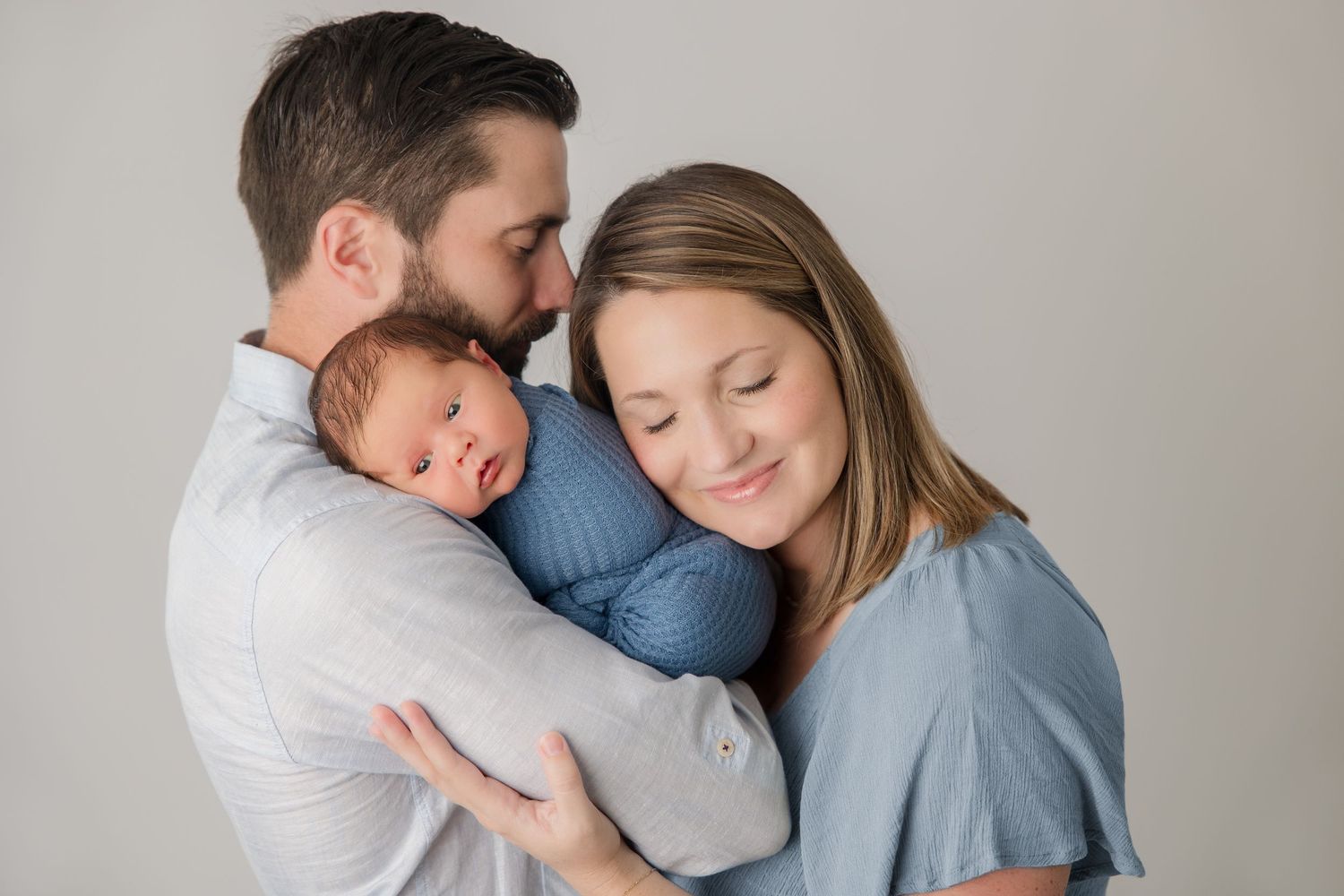 Intimate family portrait session showing tender moments against neutral backdrop.