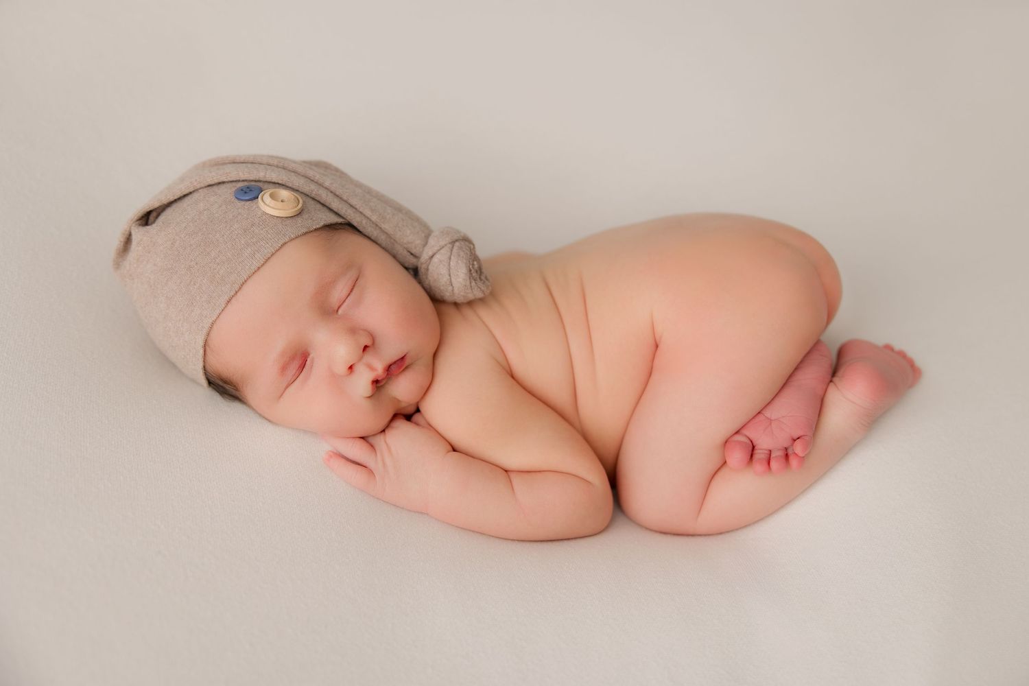 Peaceful sleeping newborn portraits on soft neutral backdrop.