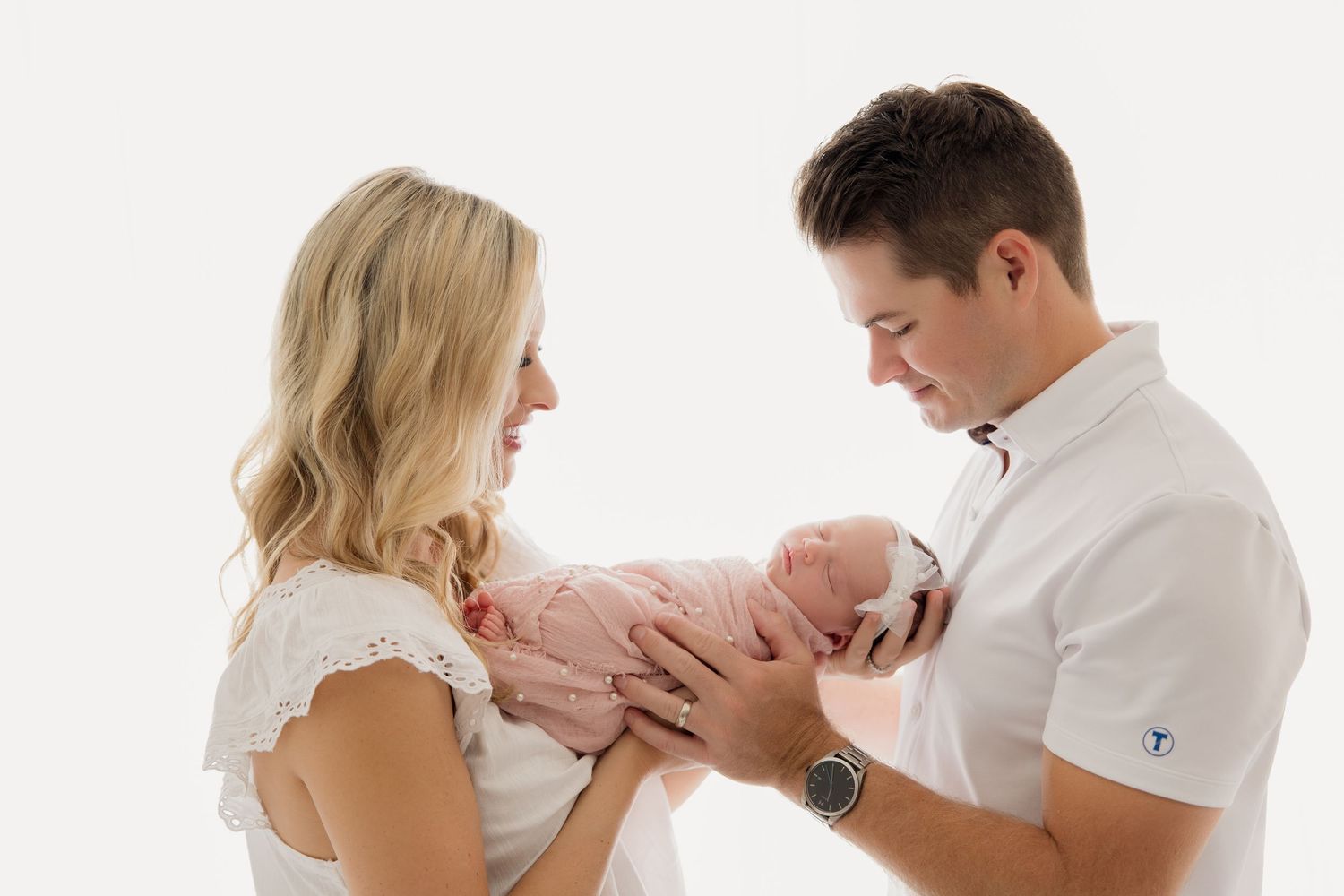 Series showing parents lovingly holding and bonding with their newborn baby in white matching outfits.