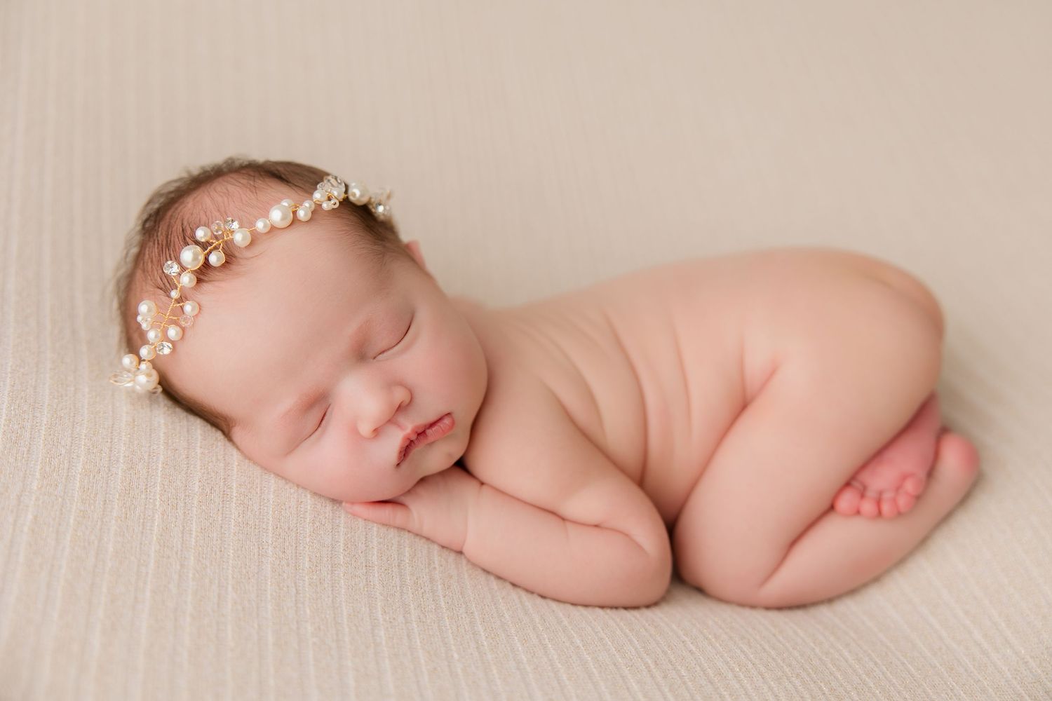 A delicate photo series showing a newborn baby sleeping peacefully on soft cream-colored fabric.