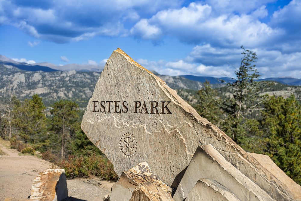 Dramatic mountain landscape with Estes Park rock formations under cloudy blue skies.