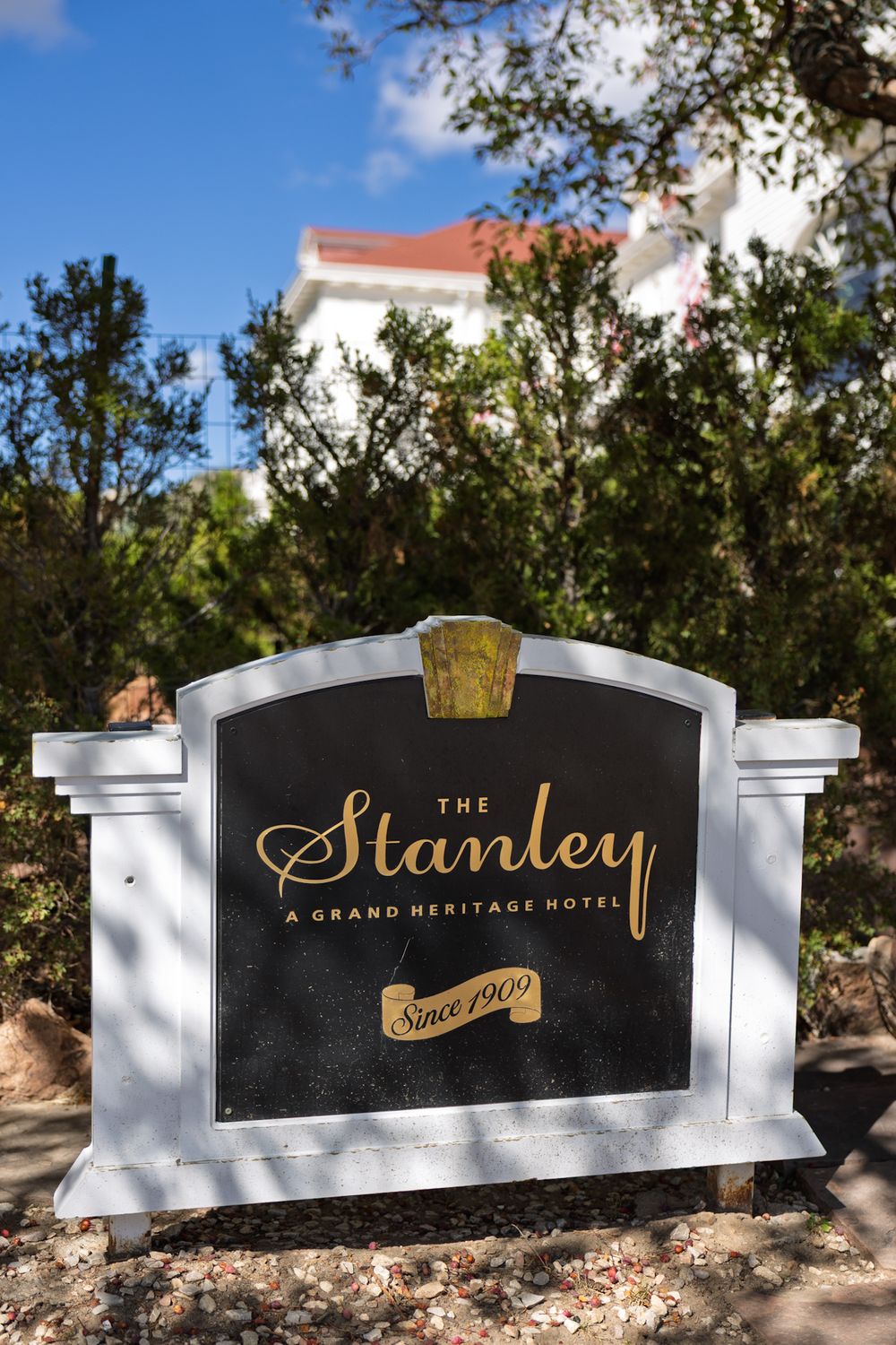 Black and gold entrance sign for The Stanley grand heritage hotel against white stone base.