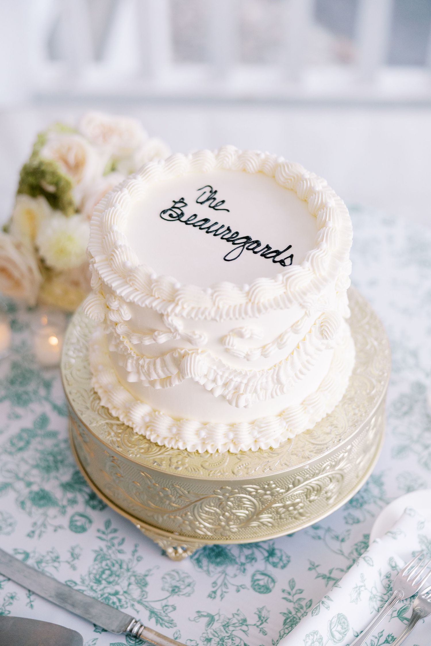 White wedding cake with delicate lace piping and scalloped details decorated in traditional buttercream frosting.