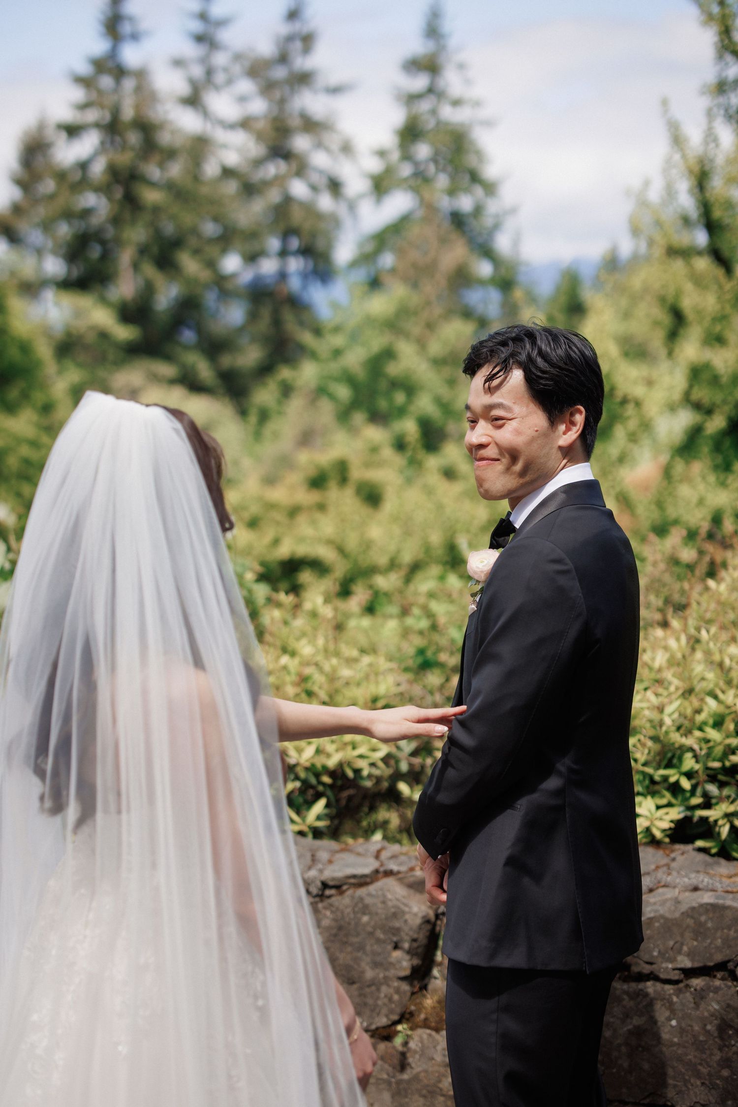A wedding couple shares a tender moment among evergreen trees and natural scenery.