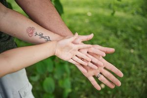 Family hands dad, mom with flower tattoo and daughter.