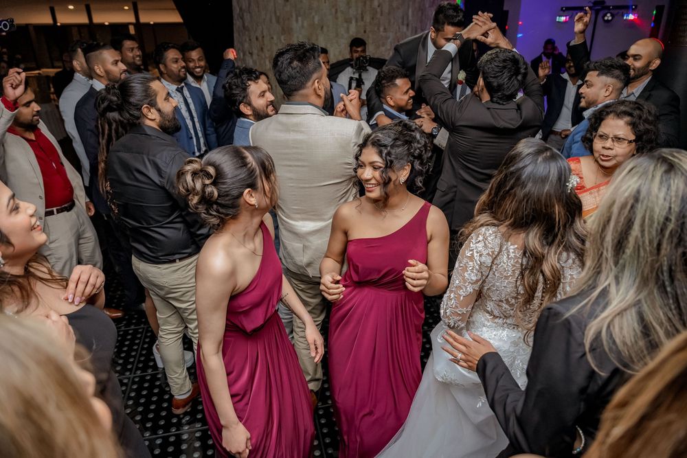 Wedding guests dance and celebrate on a crowded dance floor at an evening reception while wearing formal attire.