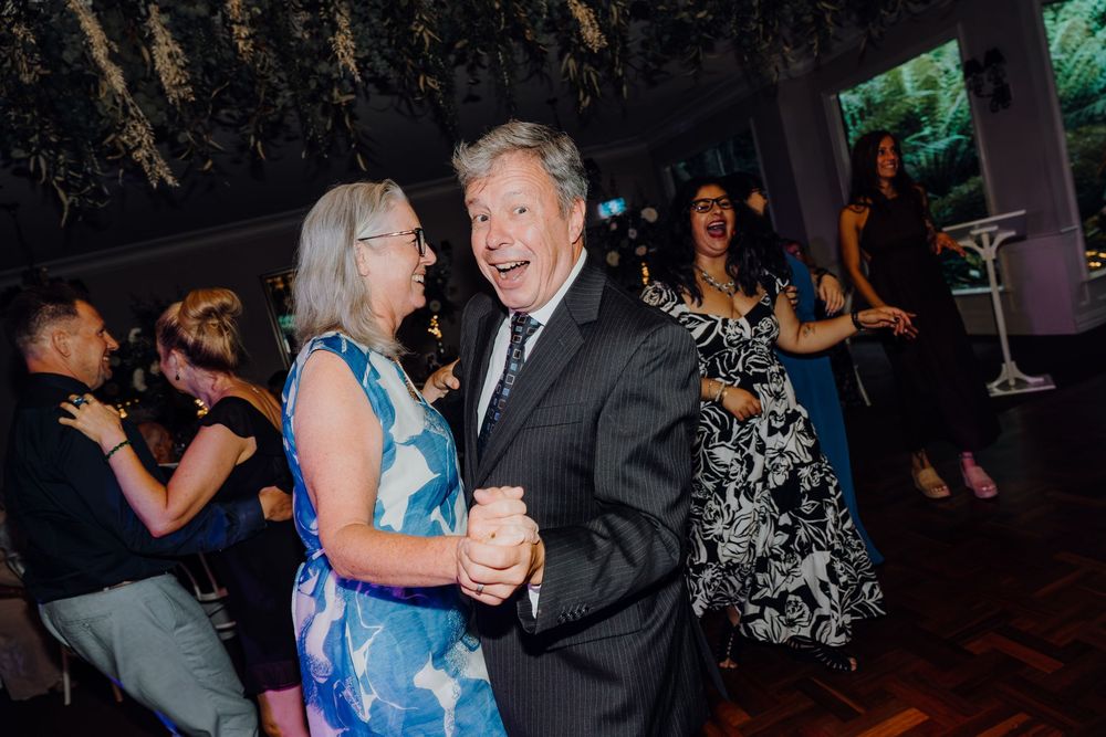 People dancing together at an evening event in formal attire on a dark dance floor.