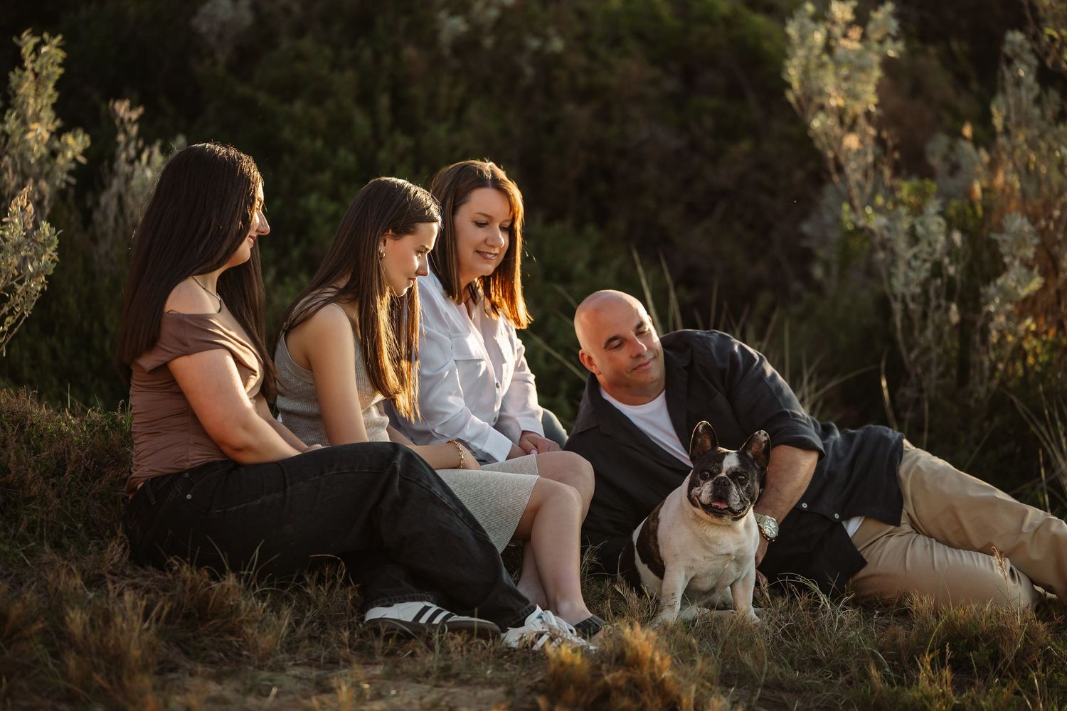 People sitting together on rocks during golden hour sunset while enjoying an intimate outdoor gathering.