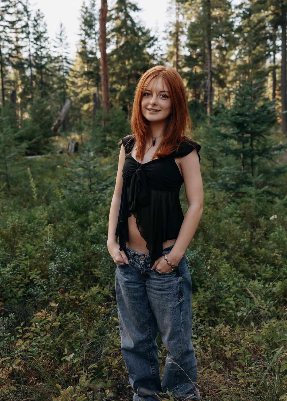 Casual outdoor portraits taken in a lush forest setting with evergreen trees.