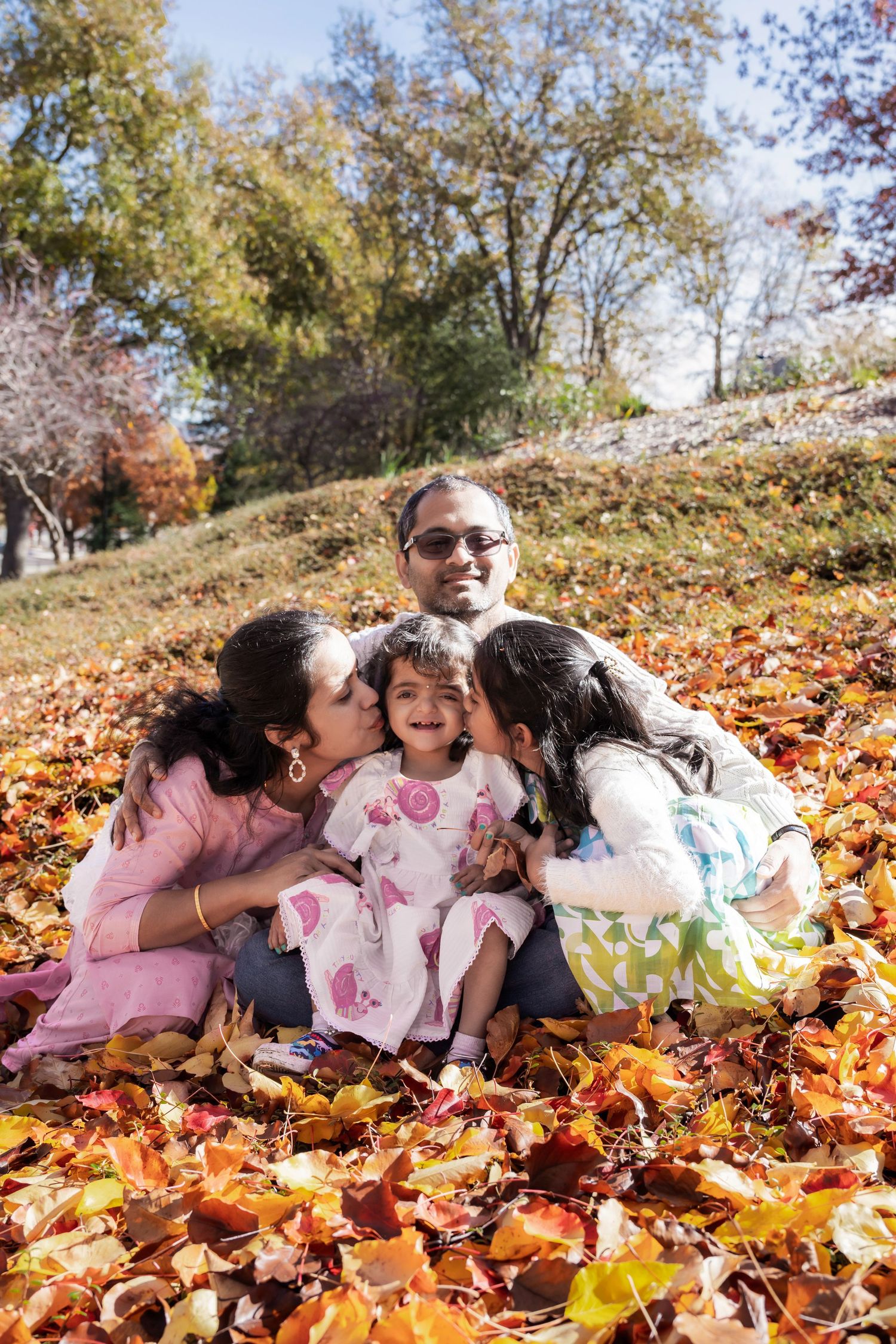 Family laying together in colorful autumn leaves during an outdoor fall photo session.