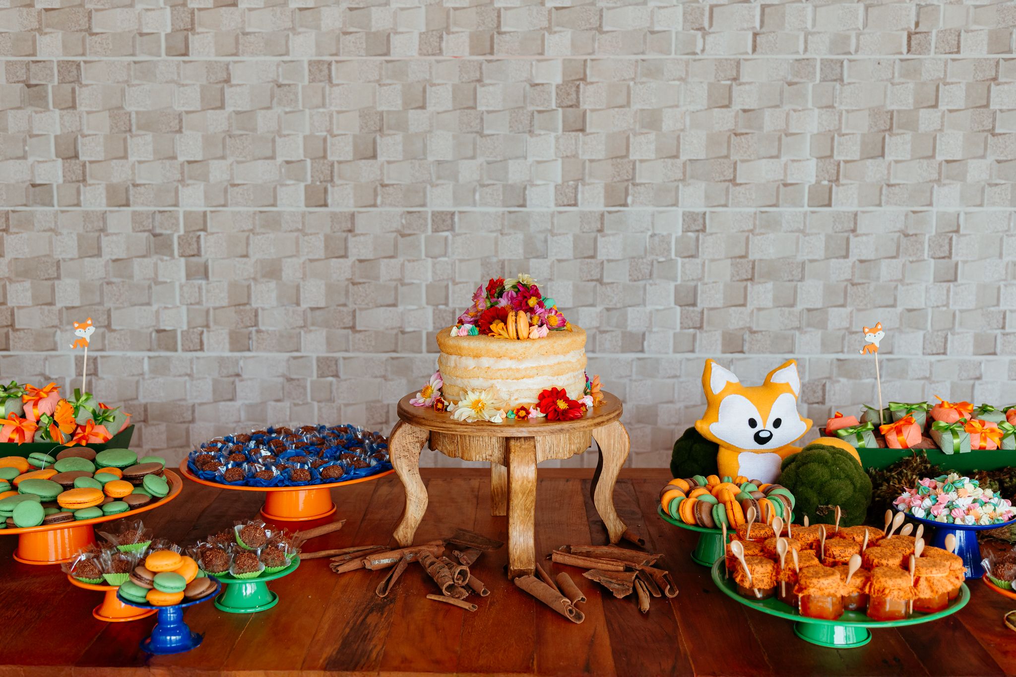 Collection of colorful desserts and appetizers arranged on a rustic wooden table at a party buffet display.