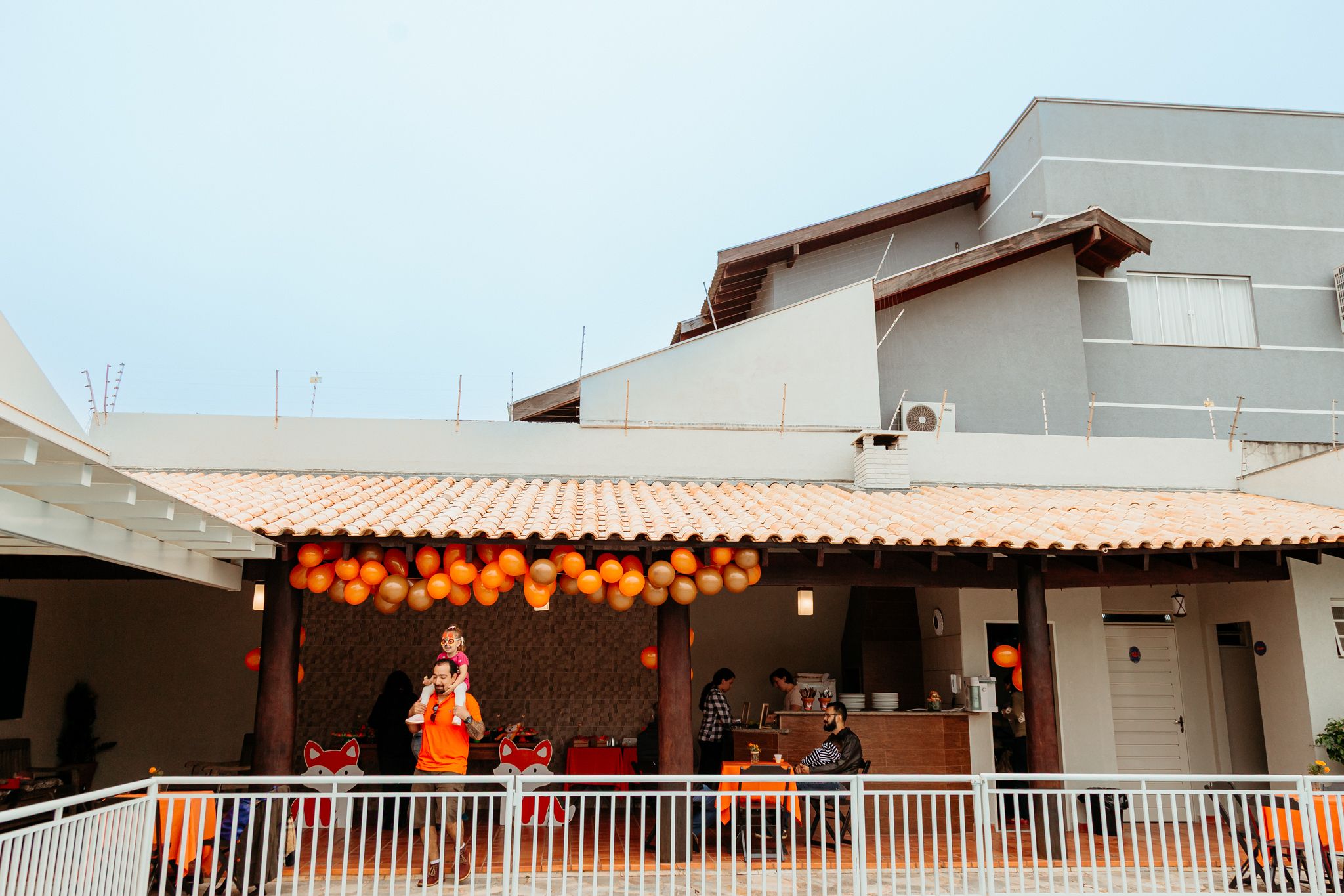 String lights and outdoor lanterns create a warm ambiance on a covered patio during sunset.
