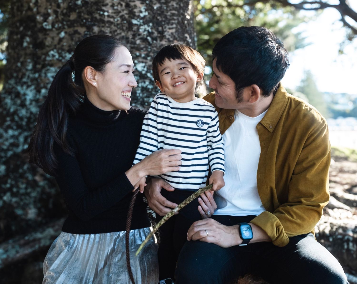 A loving family shares tender moments together while sitting outdoors during a casual photo session.auckland. daydreampics
