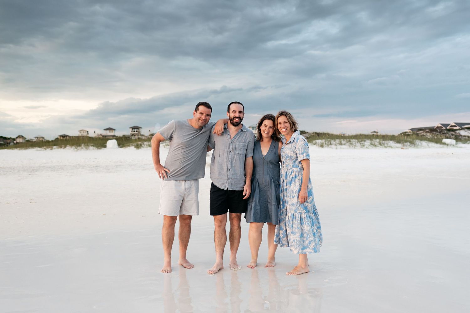 Family enjoying a sunset beach photo session wearing coordinated blue and white outfits.
