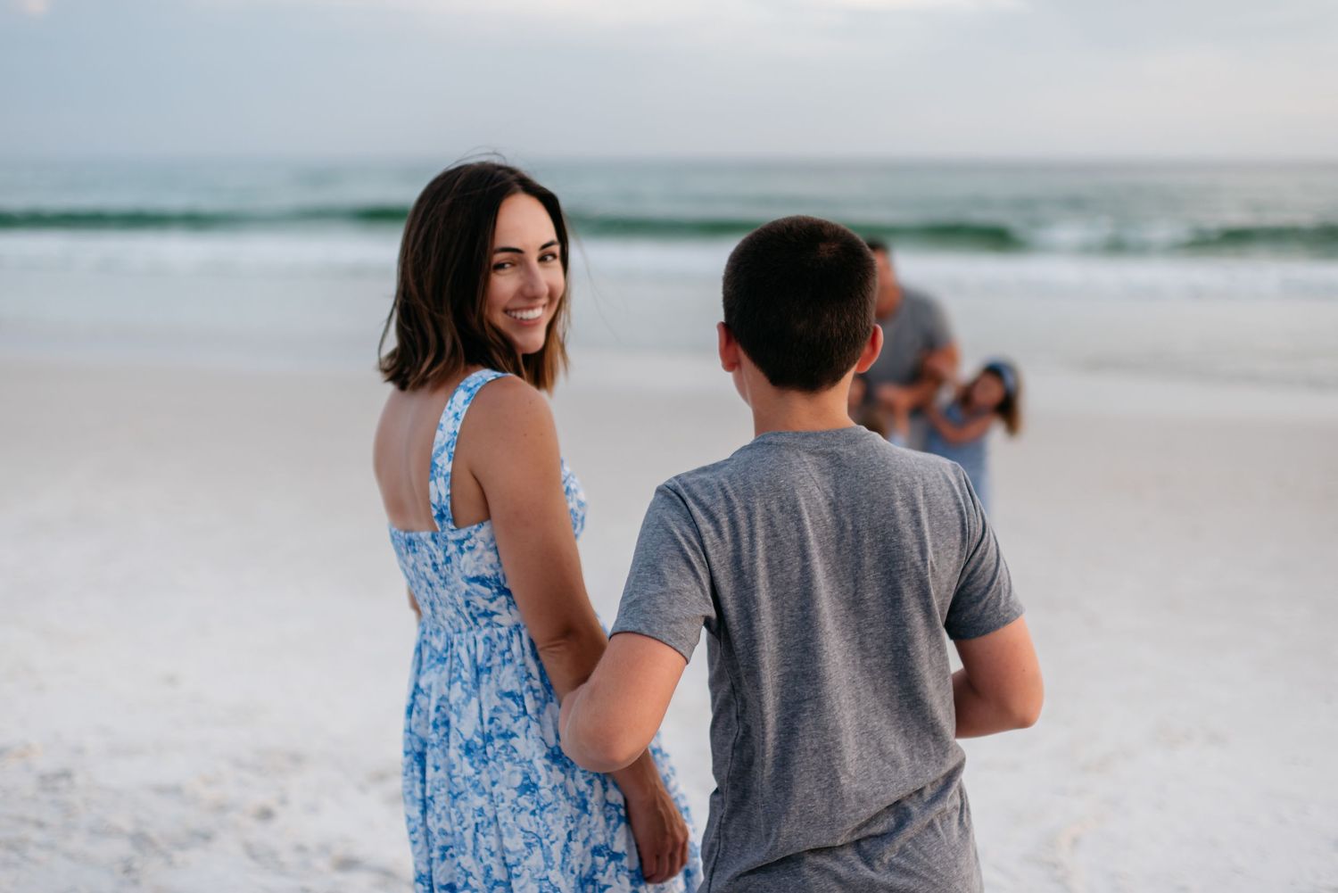 People strolling together along tranquil beach shoreline during sunset.
