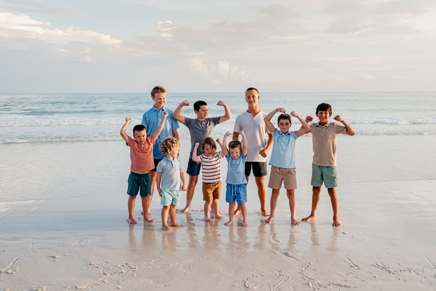 A group of people lined up in descending height order playing in the waves at the beach during sunset.
