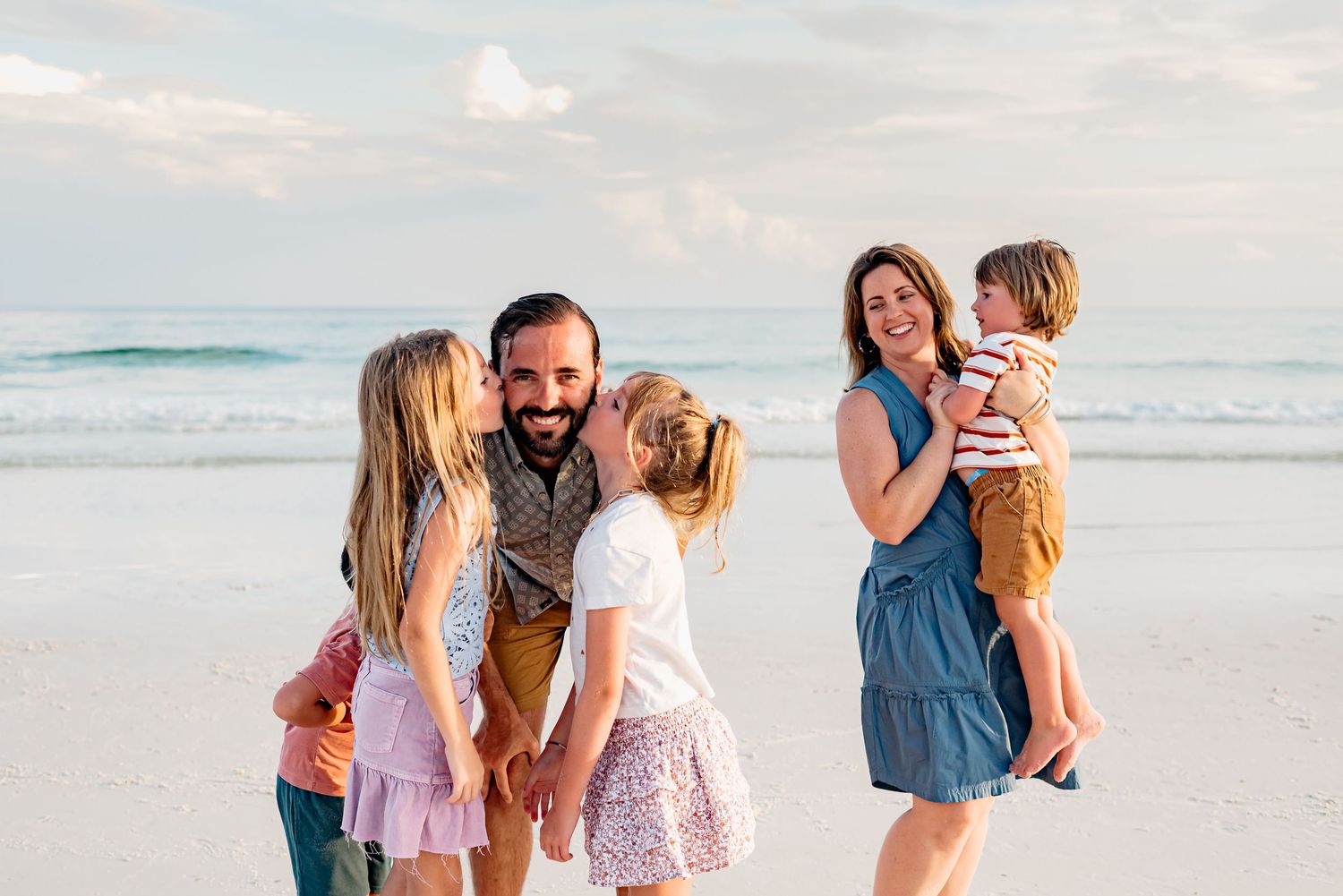 A collection of five candid family photos taken at the beach during sunset with pastel colored clothing.