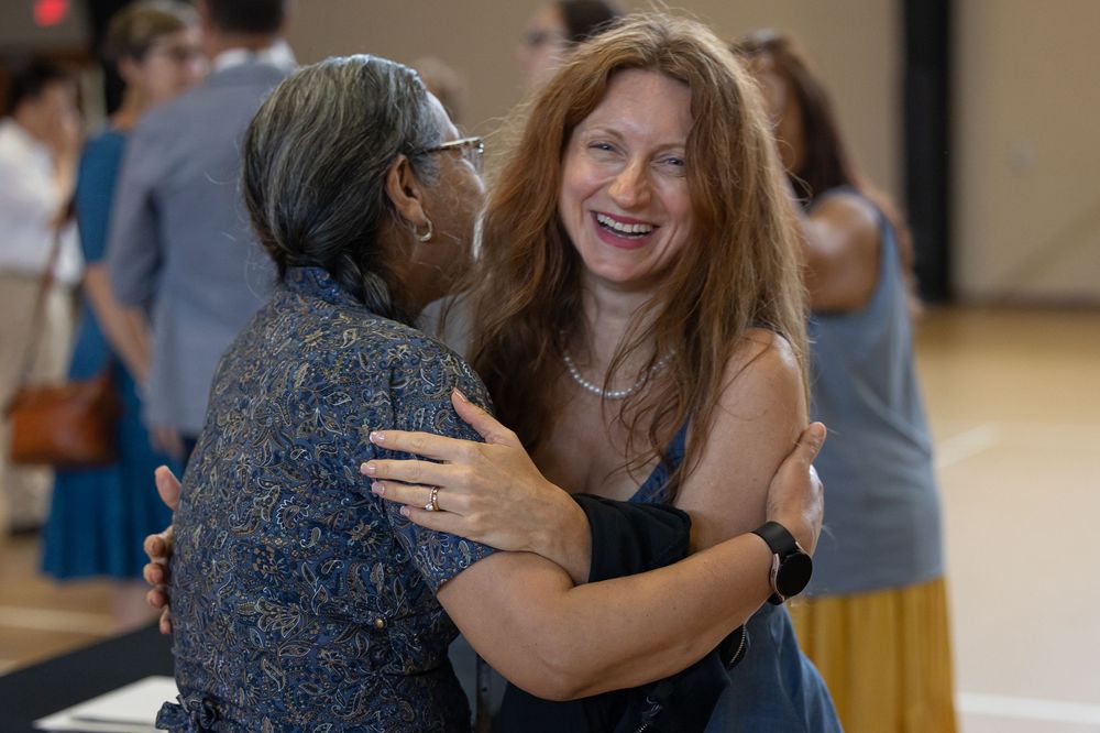 two ladies in mid hug, one smiling at the camera
