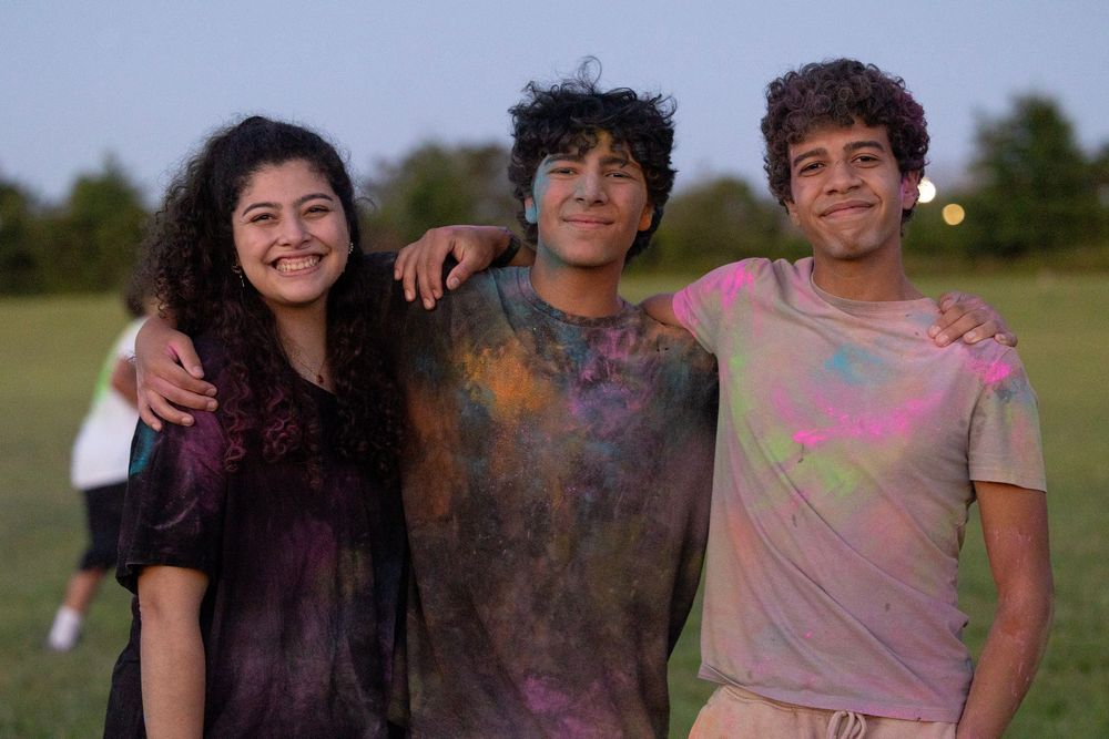 three young people hugging and smiling after a youth event