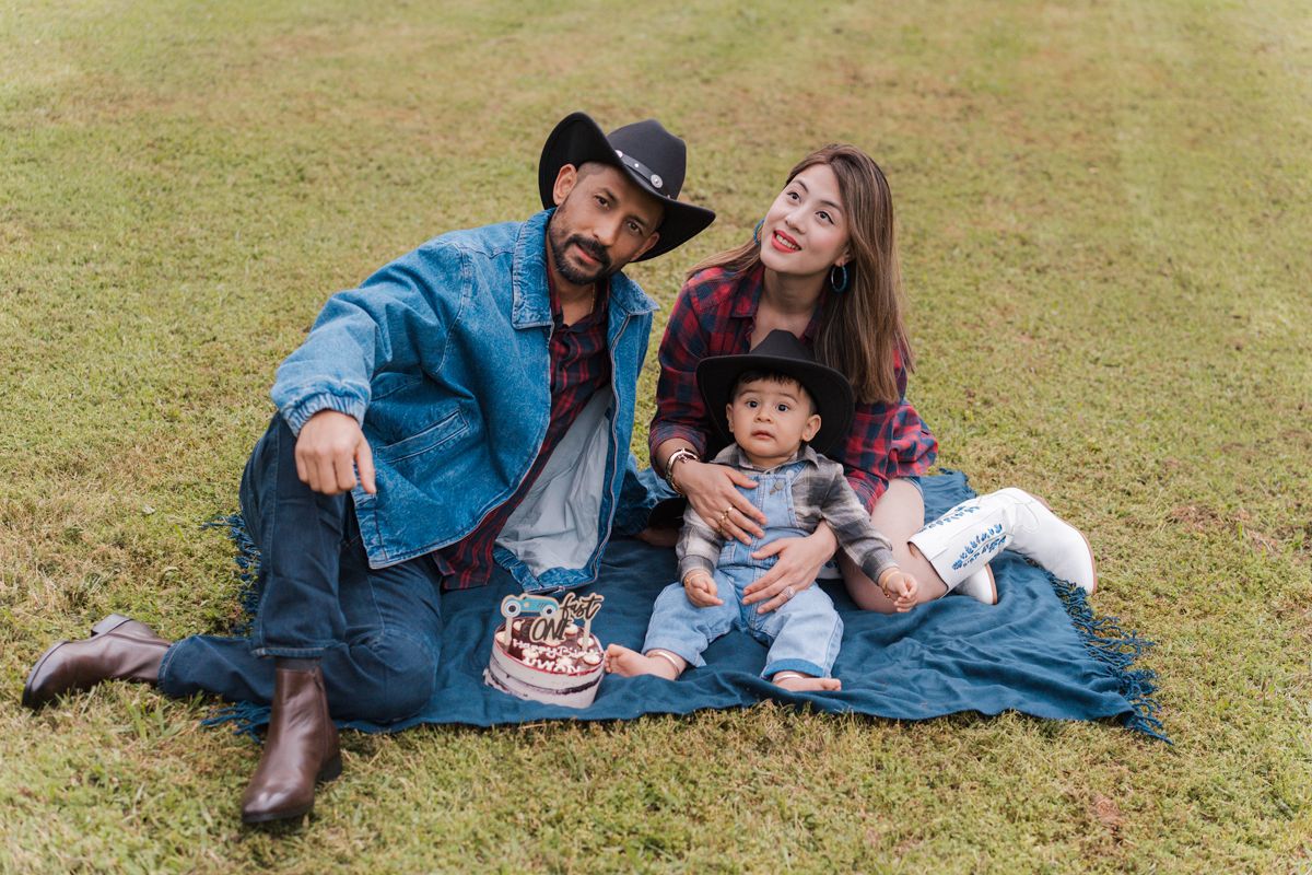 A family in denim outfit together on green grass, showcasing casual outdoor lifestyle portraits for first birthday photoshoot in Box hill