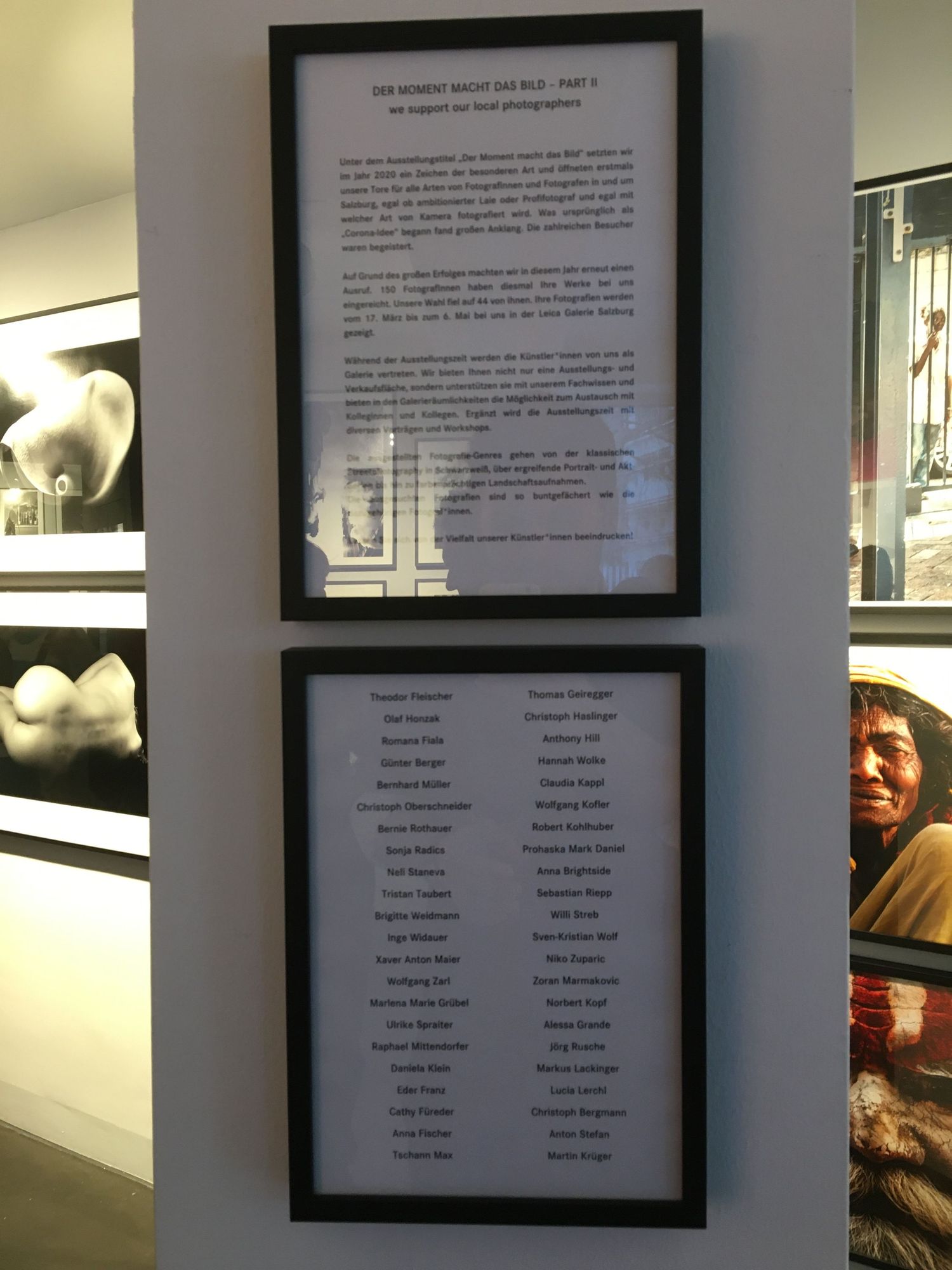 A gallery wall displays a series of black and white photographs in simple black frames against a white wall.