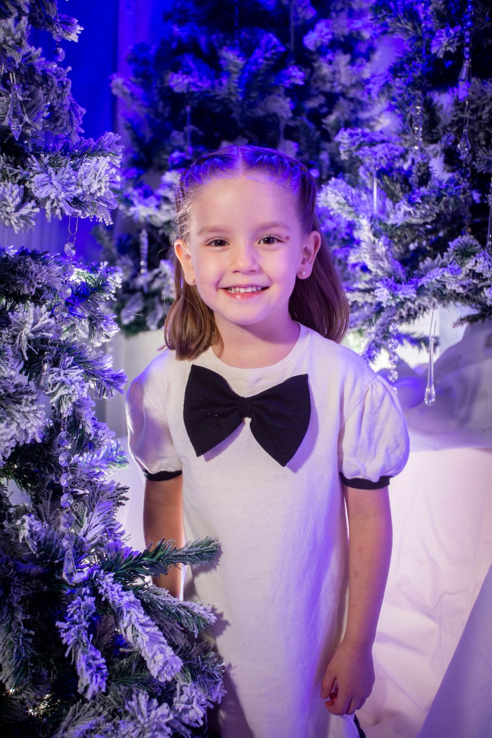 A holiday portrait in a winter wonderland setting with sparkly decorations and purple lighting effects.