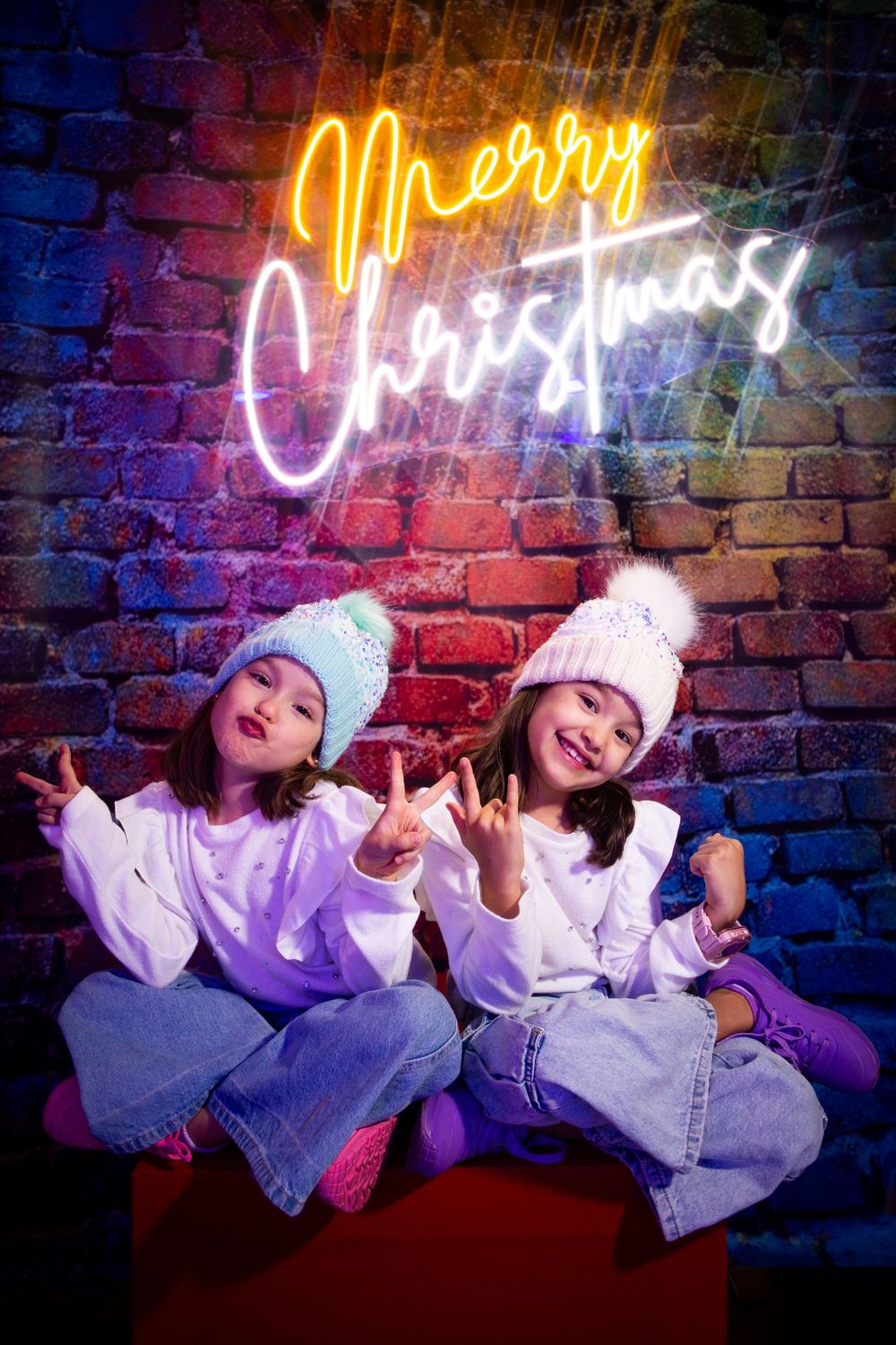 Fun photo shoot against a brick wall with neon signs and colorful lighting creating a vibrant atmosphere.