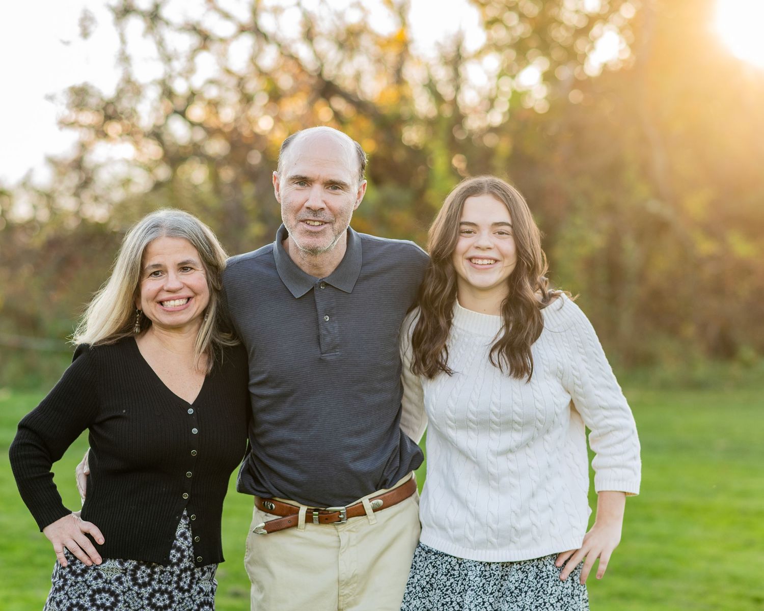 Sunset photoshoot in a grass field with golden sun flare and casual poses at golden hour.