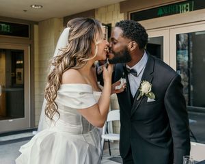Elegant wedding couple sharing romantic kisses in a building hallway with modern lighting.