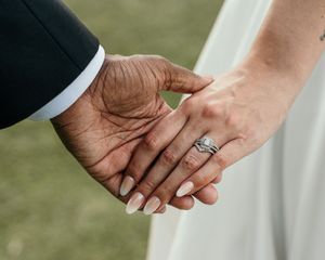 Close-up shots of hands displaying wedding rings and jewelry against a white dress background.
