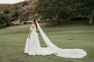 An elegant wedding couple photographed from behind while walking across a scenic grassy hillside.