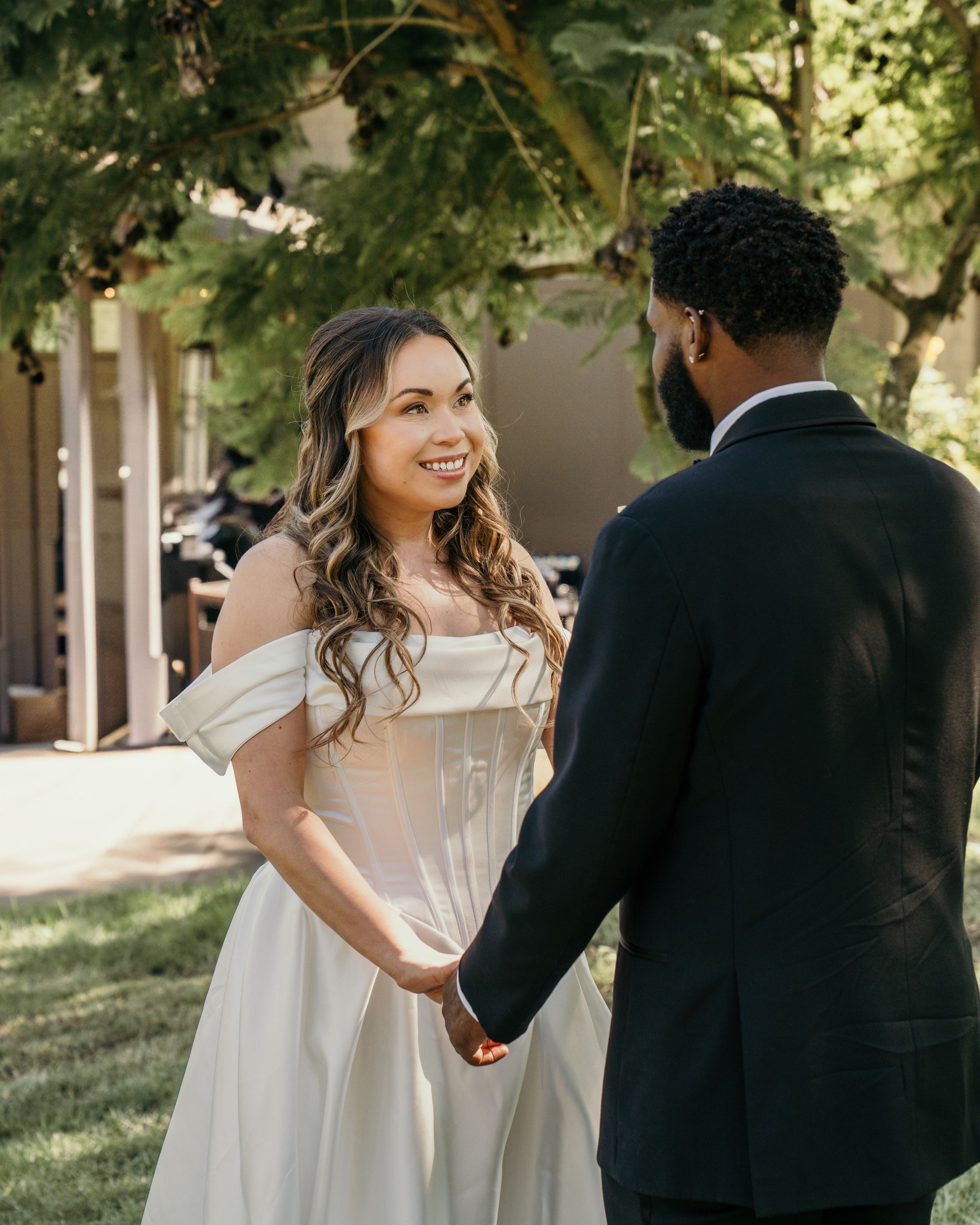 A couple in wedding attire shares intimate moments together under tree-lined paths and natural lighting.