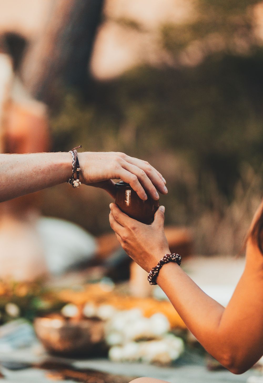 Hands gesturing during sunset with jewelry visible against golden light.
