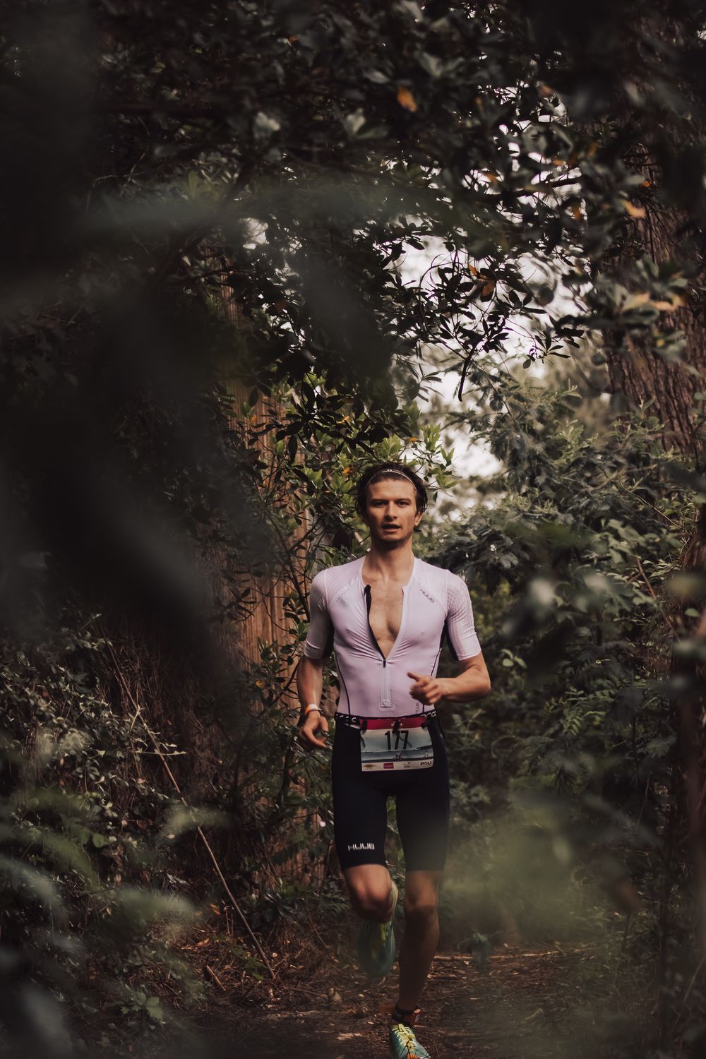 Trail runner moving through a lush forest path in athletic gear.