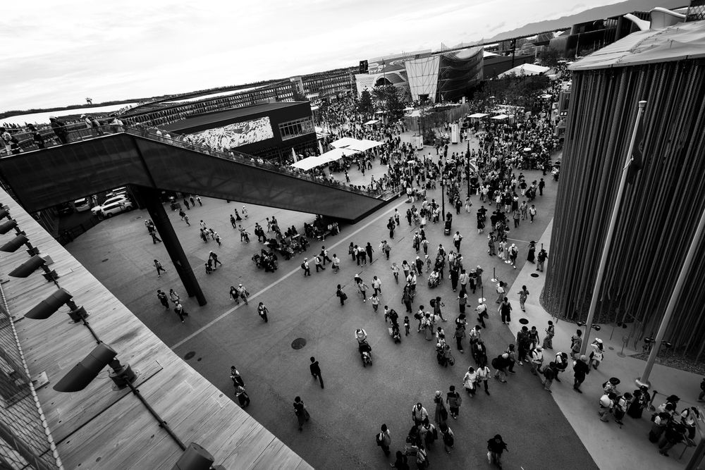 Aerial black and white view of large crowds gathered in an open plaza at a public event.